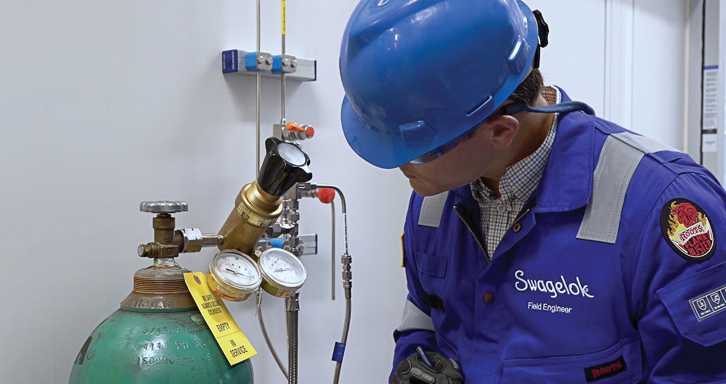 A field engineer conducting an evaluation near tubes, pressure gauges, tanks, and valves