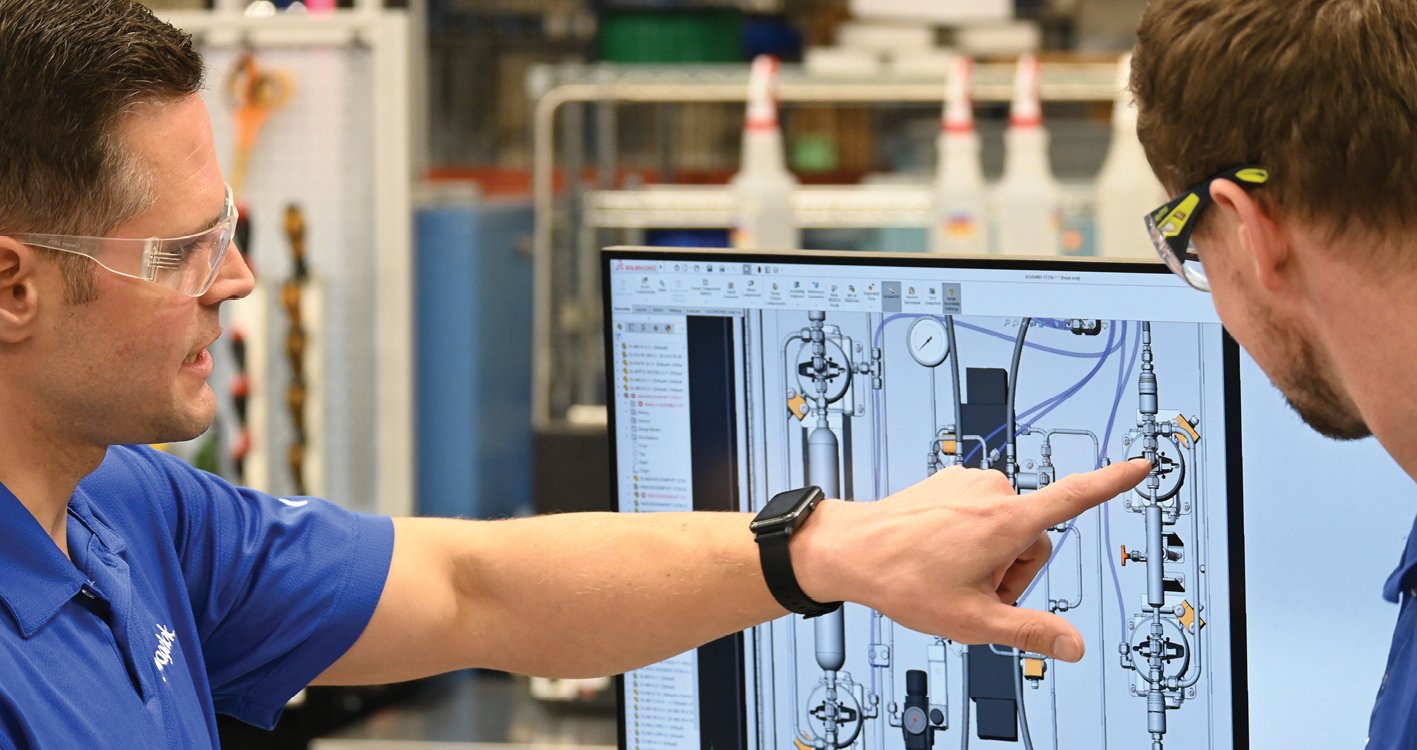 Two associates working at a computer reviewing the design and assembly of a fluid system solution